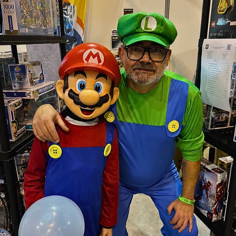 Jean-Louis Viale, fondateur de SWETM, en cosplay Luigi lors d’un festival geek aux côtés d’un jeune visiteur déguisé en Mario devant le stand de la boutique